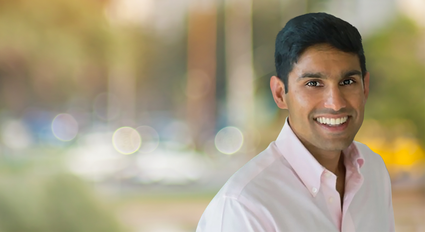 Harsh Dev Banner - Forum Financial Portrait of a smiling man in a pale pink shirt outdoors with a soft blurred background (bokeh).